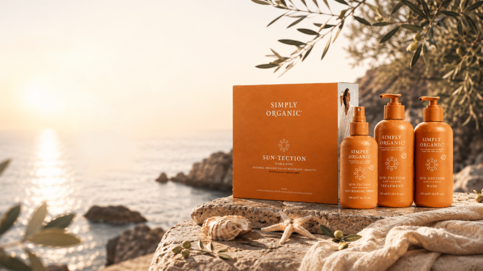 Simply Organic SunTection Set con box arancione e prodotti su sfondo marino